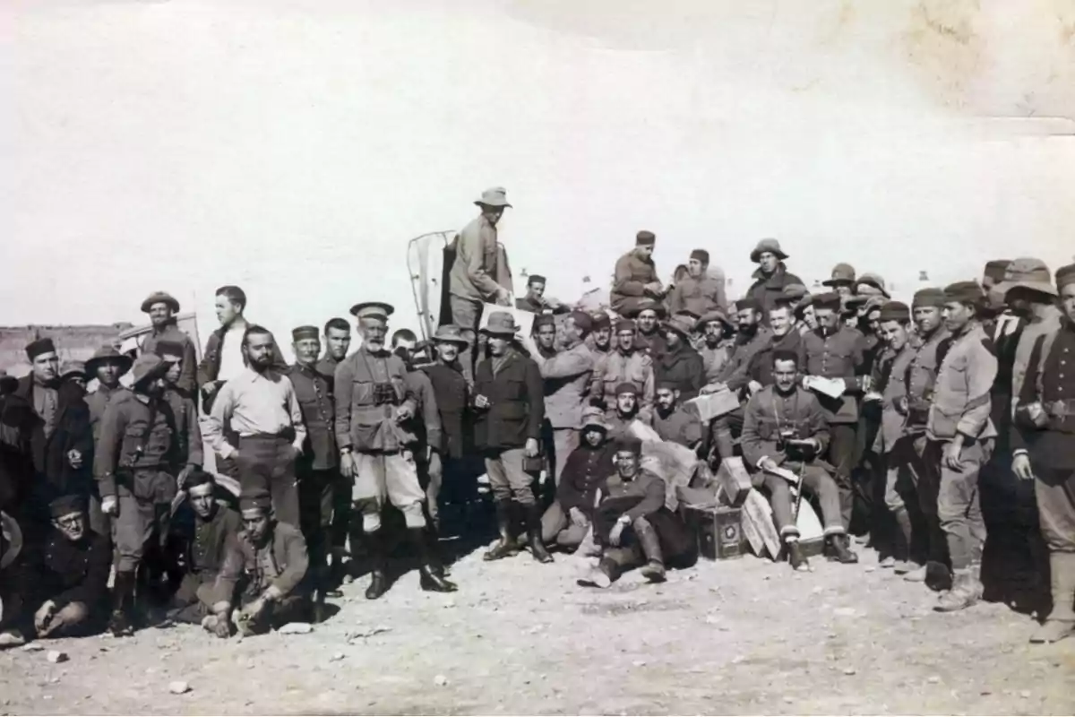 Grupo numeroso de soldados posando al aire libre en un terreno árido durante el día Grupo numeroso de soldados posando al aire libre en un terreno árido durante el día