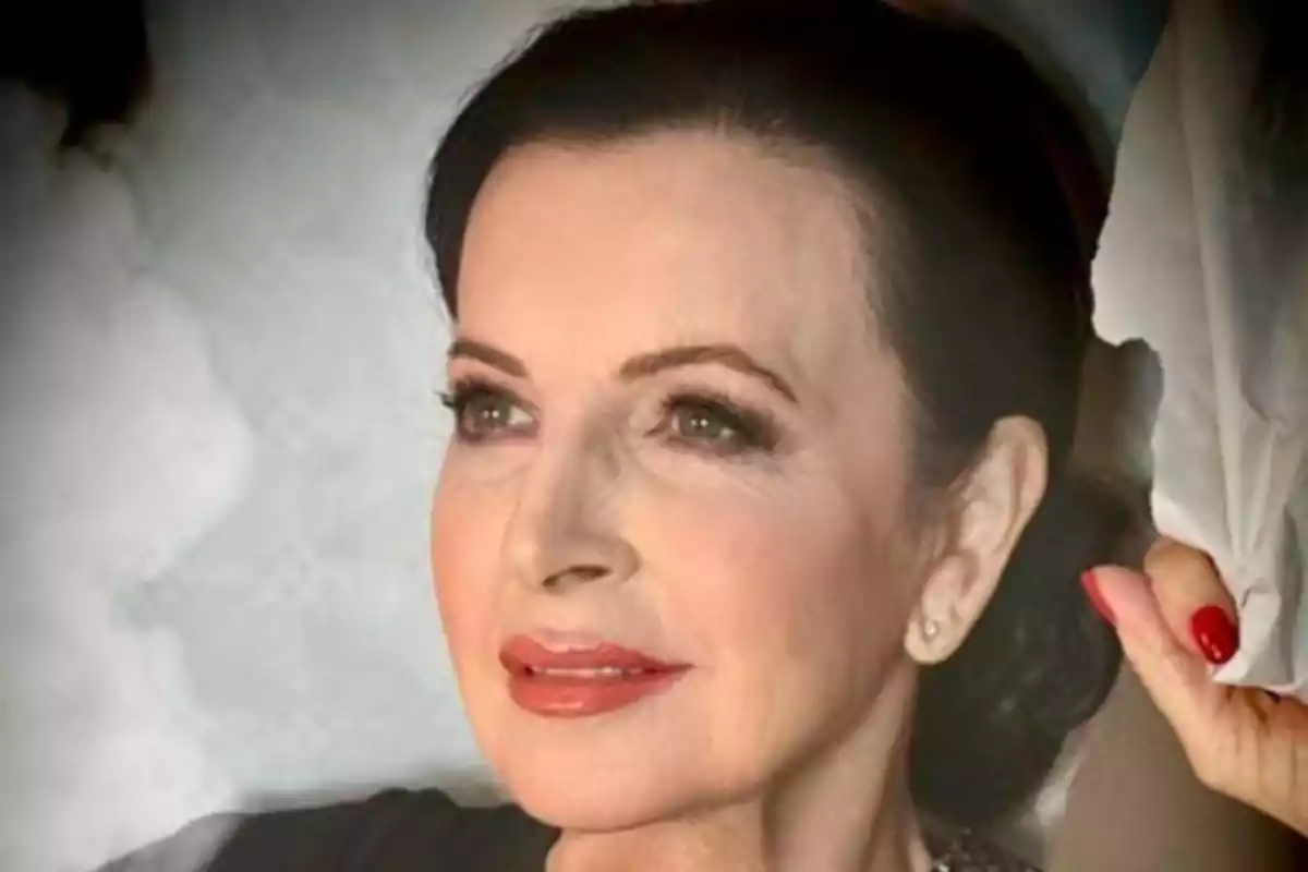 Mujer de cabello oscuro recogido con maquillaje elegante y labios rojos, mirando hacia un lado y sosteniendo una tela blanca Mujer de cabello oscuro recogido con maquillaje elegante y labios rojos, mirando hacia un lado y sosteniendo una tela blanca