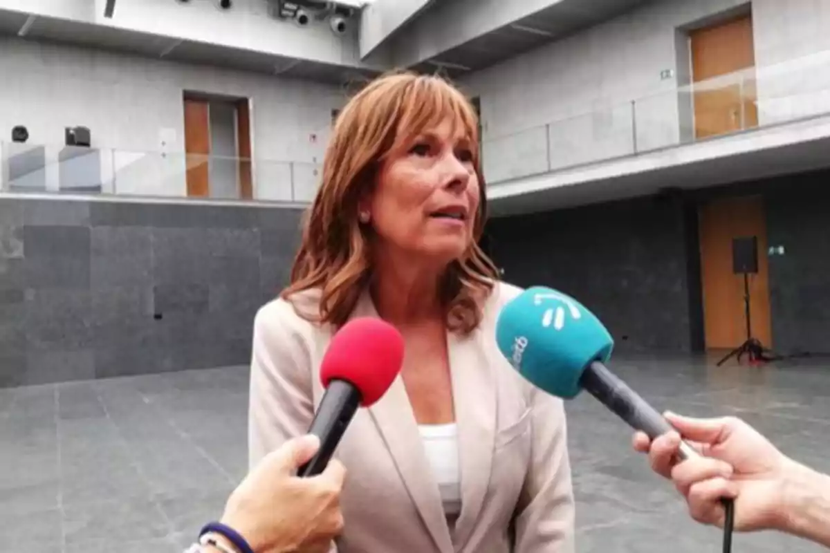 Mujer con chaqueta clara siendo entrevistada por varios periodistas en un espacio interior moderno Mujer con chaqueta clara siendo entrevistada por varios periodistas en un espacio interior moderno