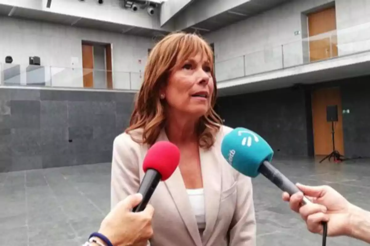 Mujer siendo entrevistada por varios periodistas con micrófonos en un espacio interior moderno