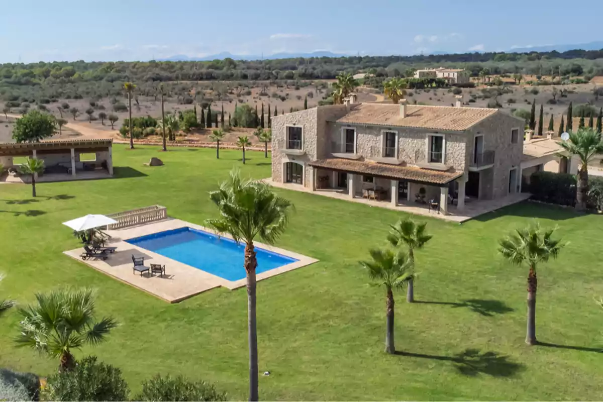 Casa de campo de piedra con piscina, césped bien cuidado, palmeras y una terraza cubierta en un entorno rural Casa de campo de piedra con piscina, césped bien cuidado, palmeras y una terraza cubierta en un entorno rural