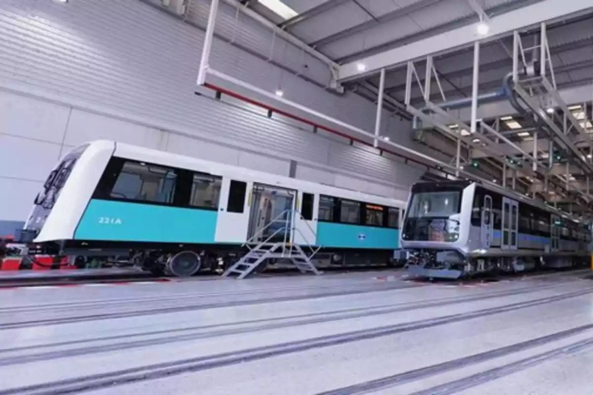 Dos trenes del metro dentro de un taller de mantenimiento con techo alto y luces industriales Dos trenes del metro dentro de un taller de mantenimiento con techo alto y luces industriales