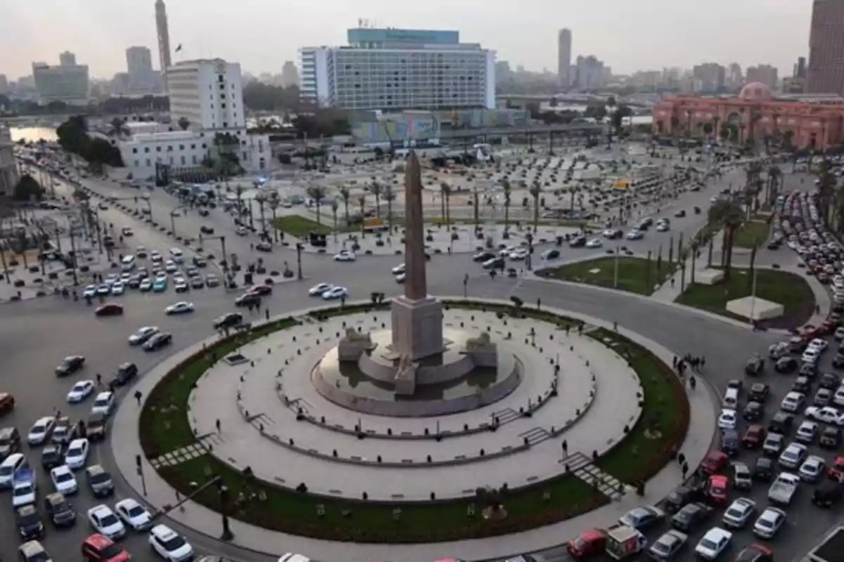 Vista aérea de una gran rotonda con un obelisco en el centro rodeada de tráfico y edificios urbanos al fondo Vista aérea de una gran rotonda con un obelisco en el centro rodeada de tráfico y edificios urbanos al fondo