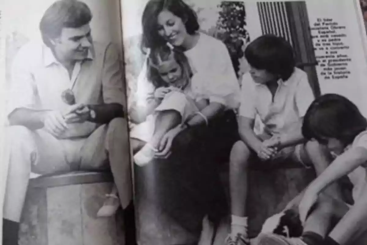 Fotografía en blanco y negro de una familia sentada al aire libre, con dos adultos y tres niños compartiendo un momento juntos Fotografía en blanco y negro de una familia sentada al aire libre, con dos adultos y tres niños compartiendo un momento juntos
