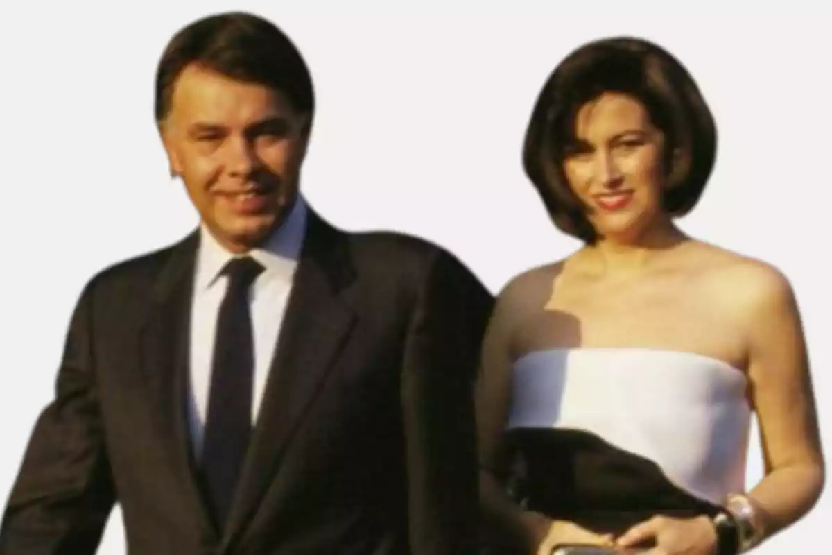 Pareja elegantemente vestida posando y sonriendo frente a un fondo claro Pareja elegantemente vestida posando y sonriendo frente a un fondo claro