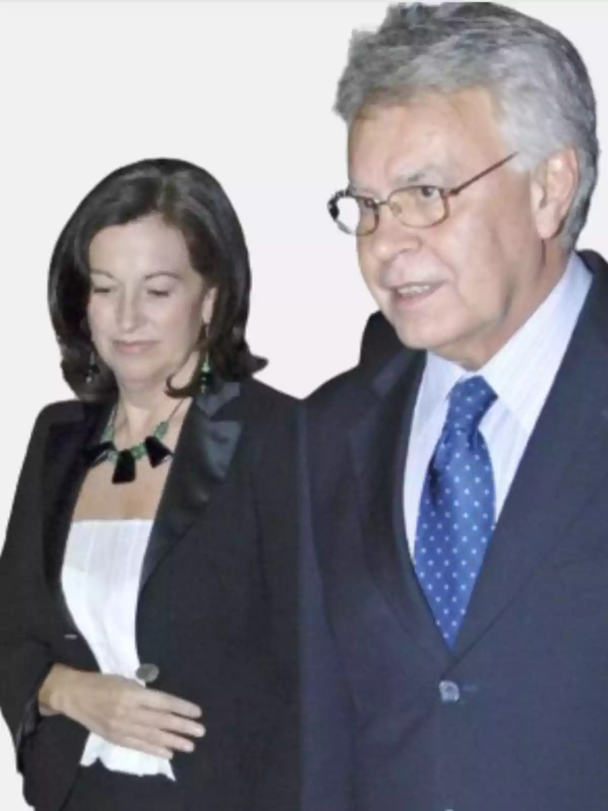 Una mujer y un hombre vestidos de manera formal posan juntos frente a un fondo claro Una mujer y un hombre vestidos de manera formal posan juntos frente a un fondo claro