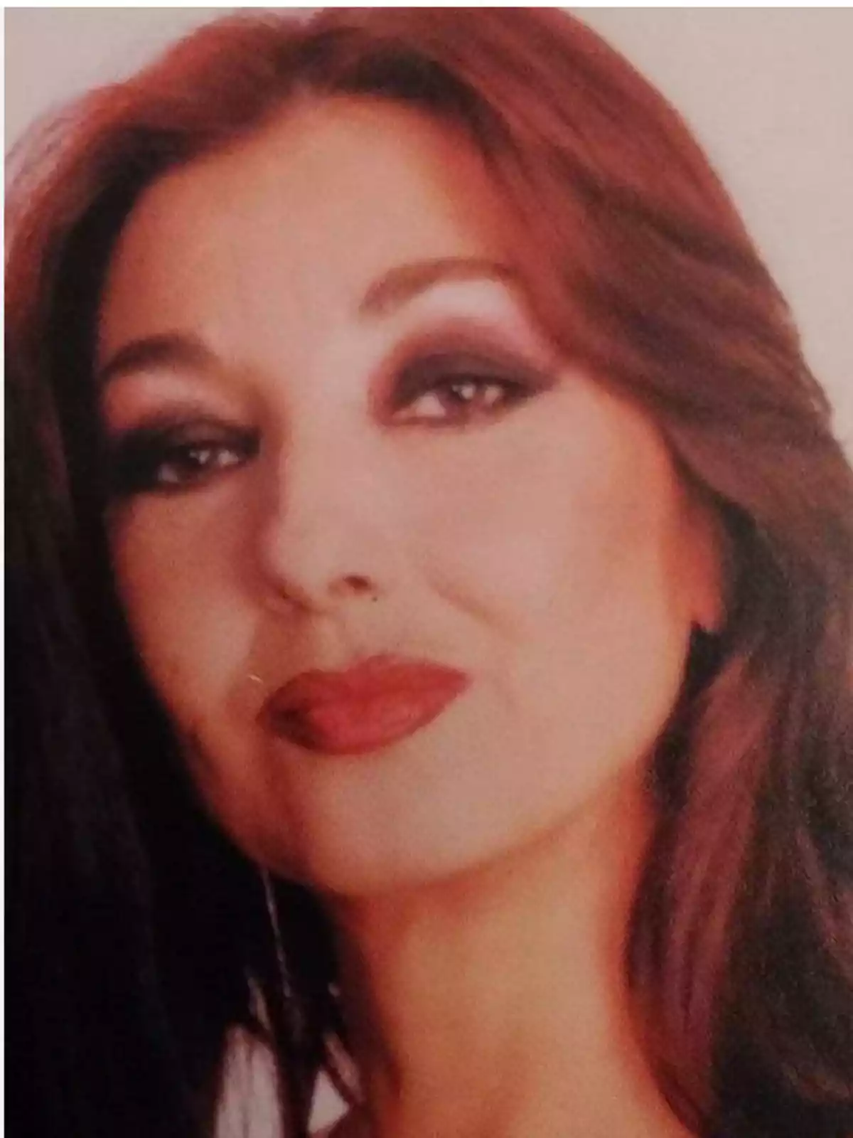 Mujer de cabello castaño rojizo y maquillaje marcado mirando a la cámara con expresión serena Mujer de cabello castaño rojizo y maquillaje marcado mirando a la cámara con expresión serena