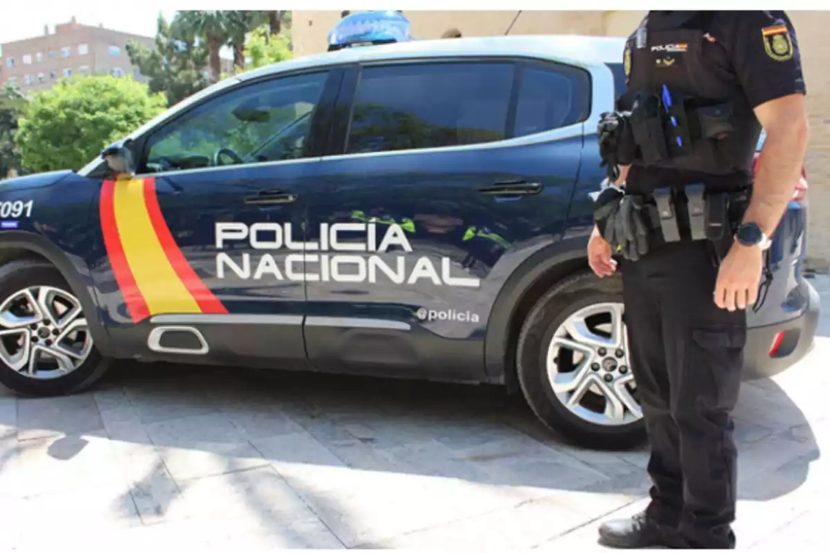 Patrulla de la Policía Nacional de España con un agente de pie junto a un coche policial Patrulla de la Policía Nacional de España con un agente de pie junto a un coche policial
