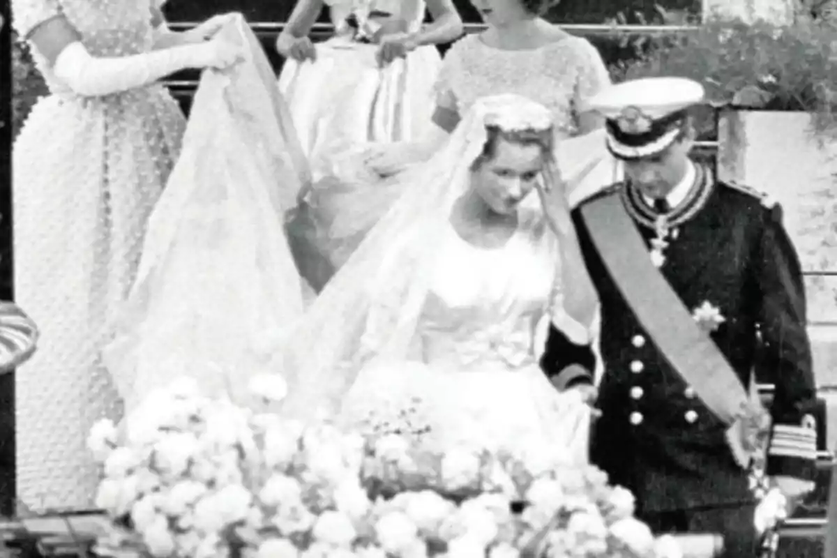 Pareja de recién casados con vestimenta formal y elegante saliendo de una ceremonia acompañados por damas de honor en un ambiente decorado con flores