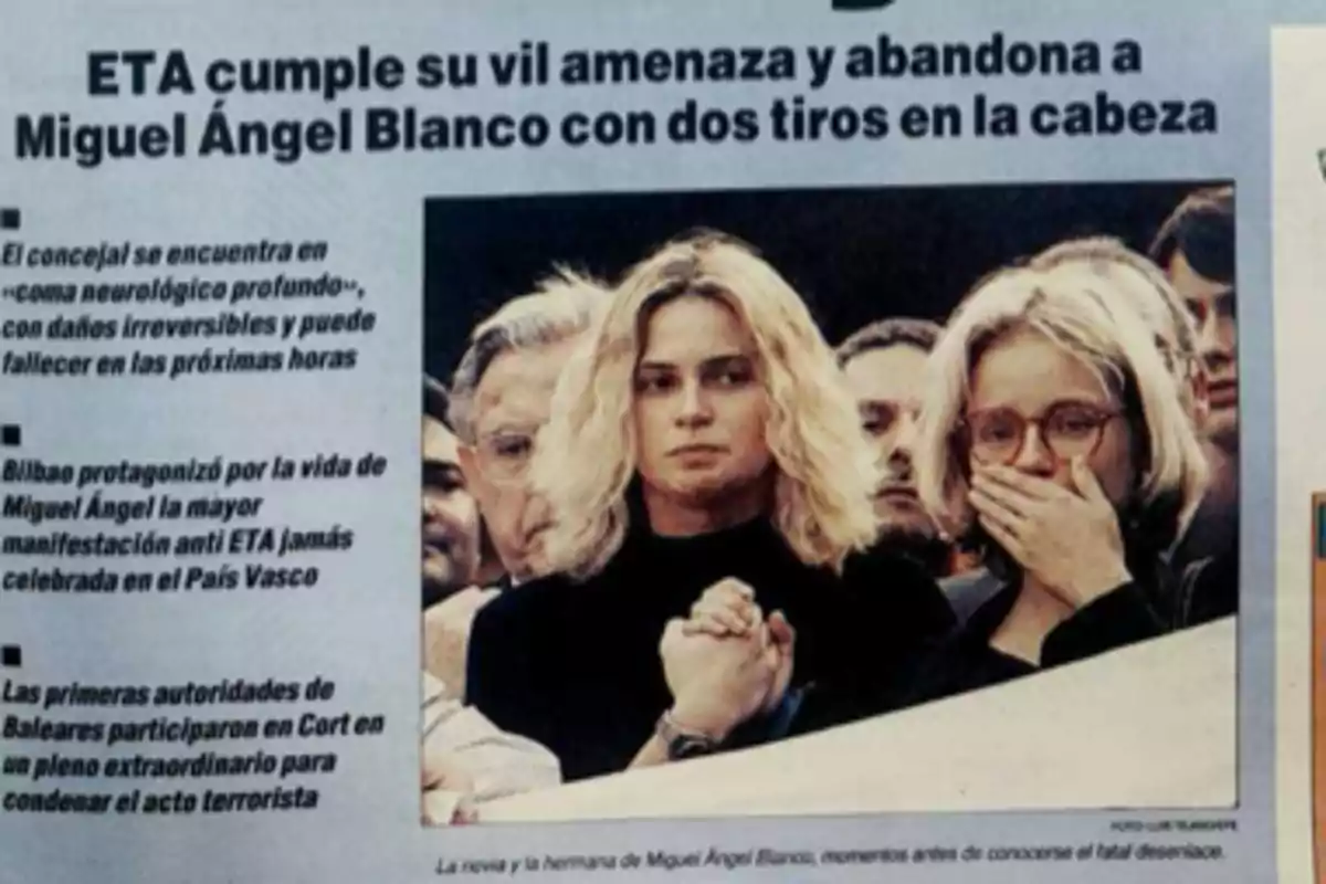 Portada de periódico con el titular sobre el asesinato de Miguel Ángel Blanco y una fotografía de dos mujeres visiblemente afectadas entre una multitud Portada de periódico con el titular sobre el asesinato de Miguel Ángel Blanco y una fotografía de dos mujeres visiblemente afectadas entre una multitud