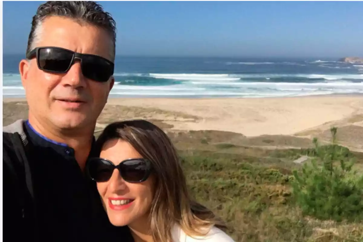 Pareja con gafas de sol tomándose una selfie en la playa con el mar de fondo Pareja con gafas de sol tomándose una selfie en la playa con el mar de fondo