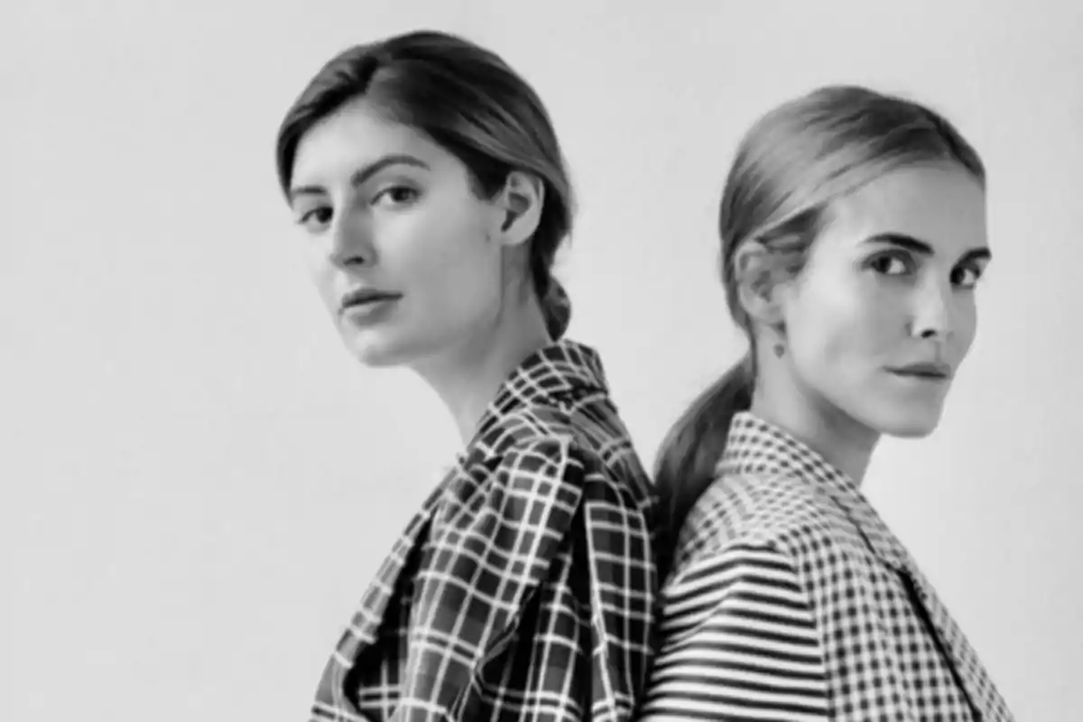 Dos mujeres de espaldas entre sí mirando a la cámara con ropa de estampados diferentes en blanco y negro Dos mujeres de espaldas entre sí mirando a la cámara con ropa de estampados diferentes en blanco y negro
