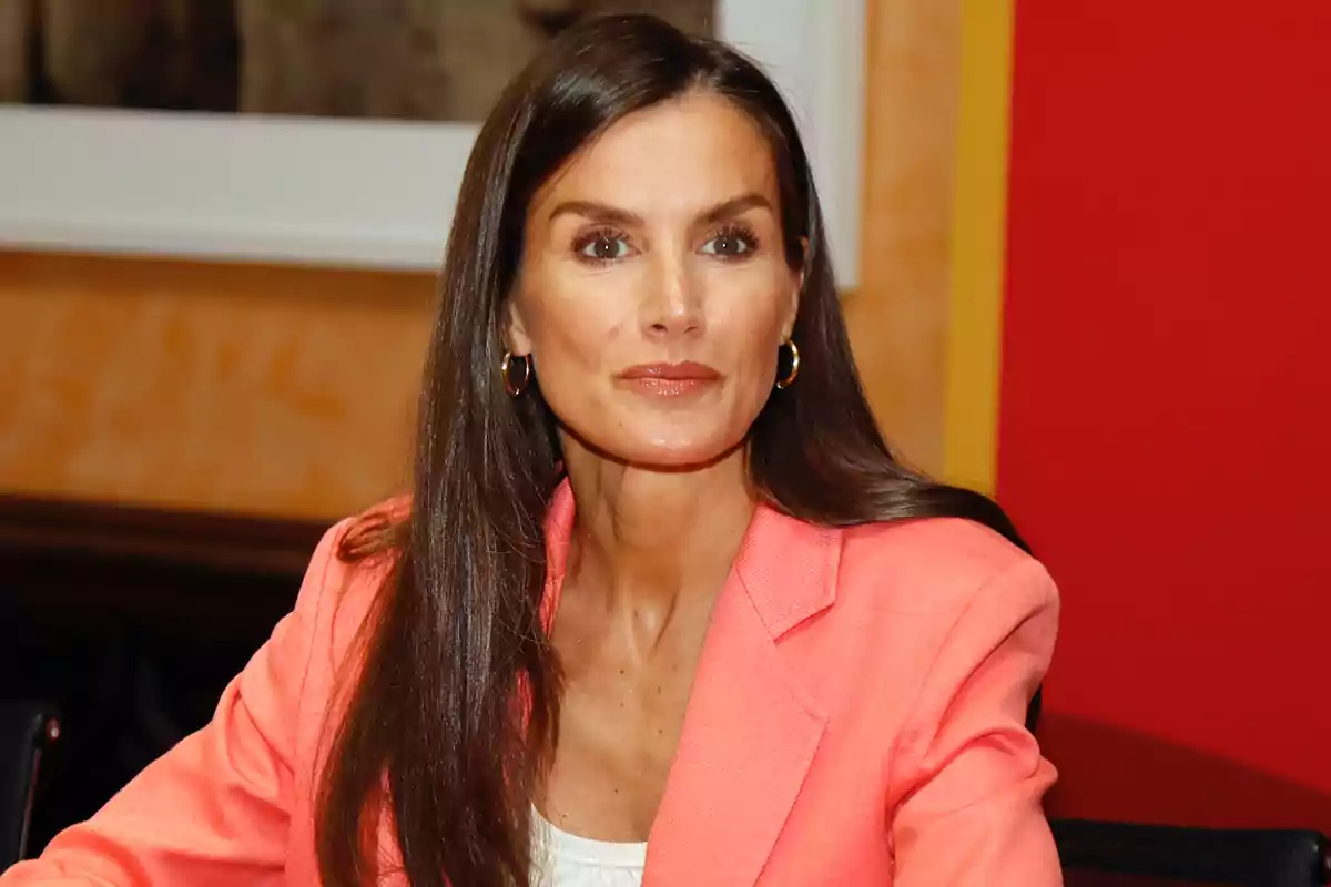 Mujer de cabello largo y lacio con chaqueta rosa sentada en un ambiente interior colorido Mujer de cabello largo y lacio con chaqueta rosa sentada en un ambiente interior colorido