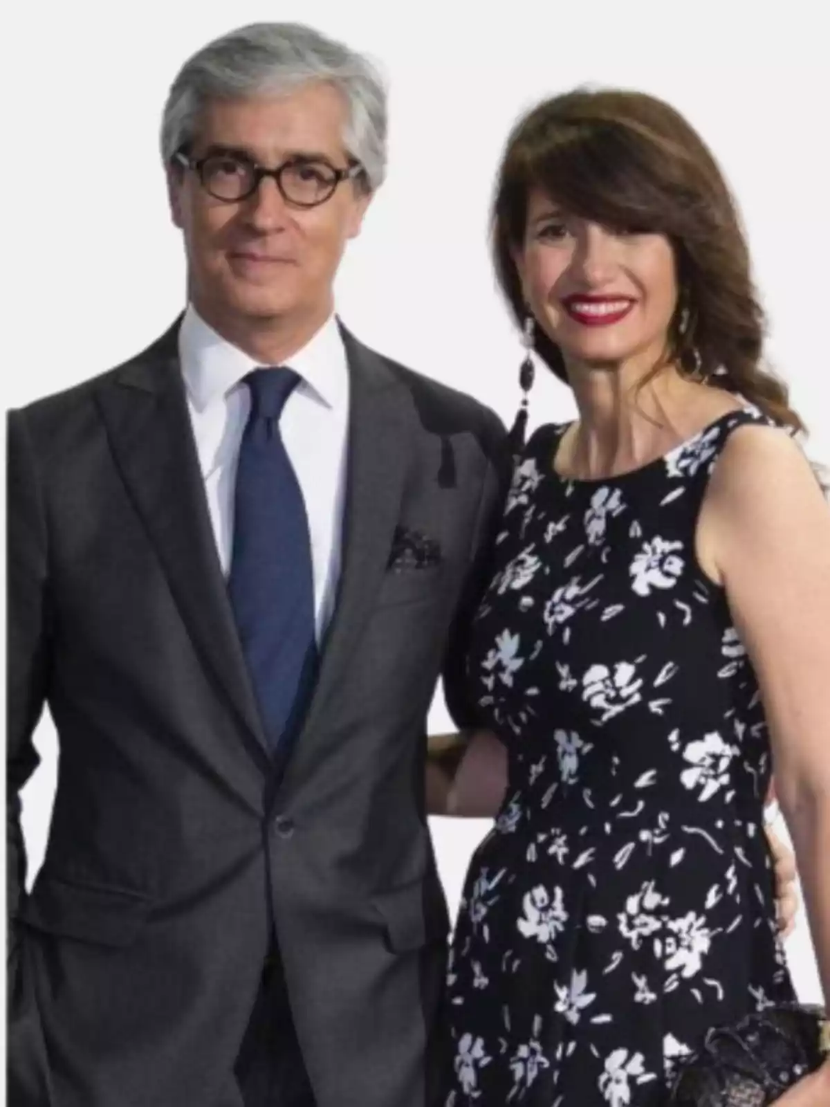 Pareja posando elegantemente, el hombre lleva traje gris y corbata azul, la mujer viste un vestido negro con estampado floral blanco y ambos sonríen Pareja posando elegantemente, el hombre lleva traje gris y corbata azul, la mujer viste un vestido negro con estampado floral blanco y ambos sonríen