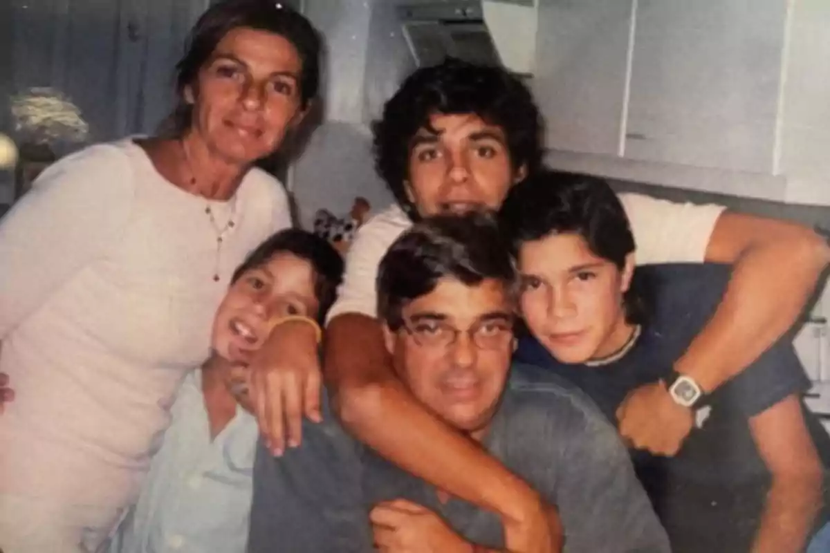 Familia posando junta en una cocina con expresiones alegres y abrazos entre ellos Familia posando junta en una cocina con expresiones alegres y abrazos entre ellos
