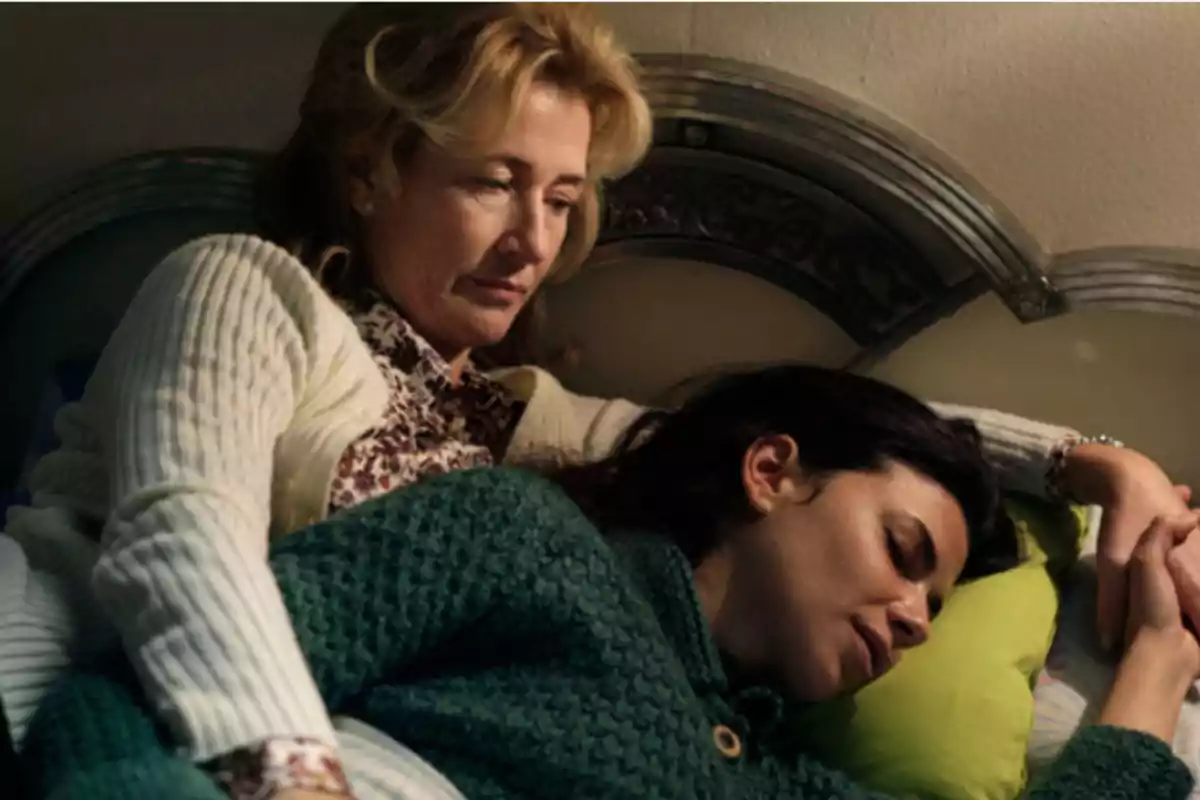 Dos mujeres están acostadas en una cama, una de ellas abraza a la otra de manera reconfortante mientras la observa con ternura Dos mujeres están acostadas en una cama, una de ellas abraza a la otra de manera reconfortante mientras la observa con ternura