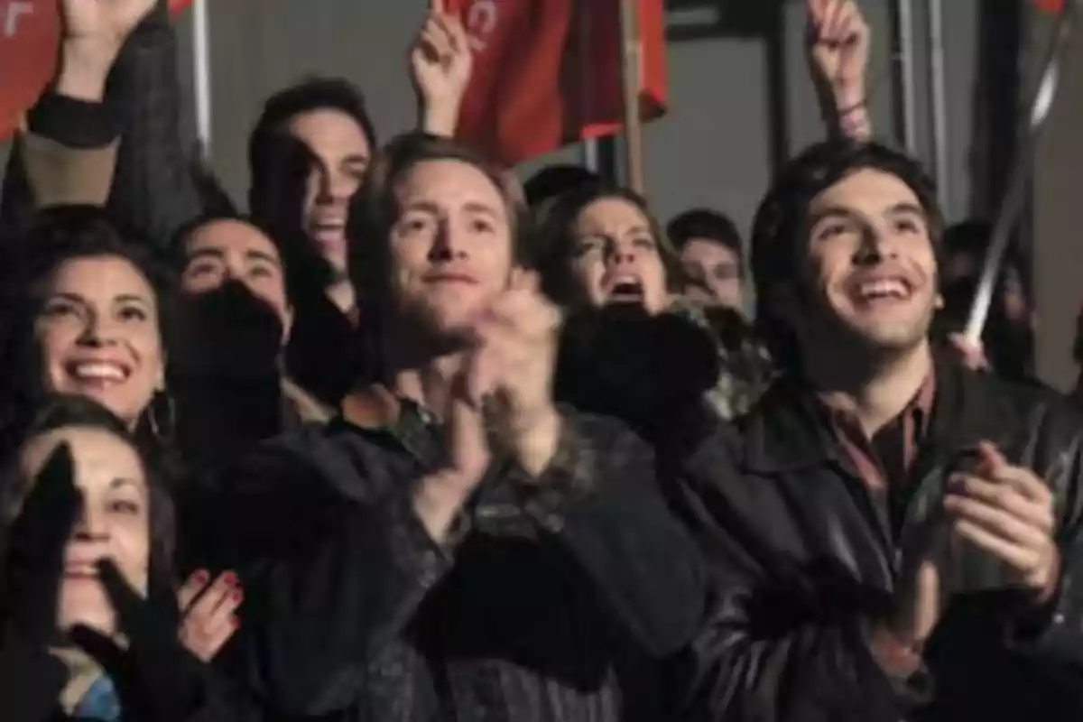 Grupo de personas sonríe y aplaude en un evento al aire libre durante la noche Grupo de personas sonríe y aplaude en un evento al aire libre durante la noche