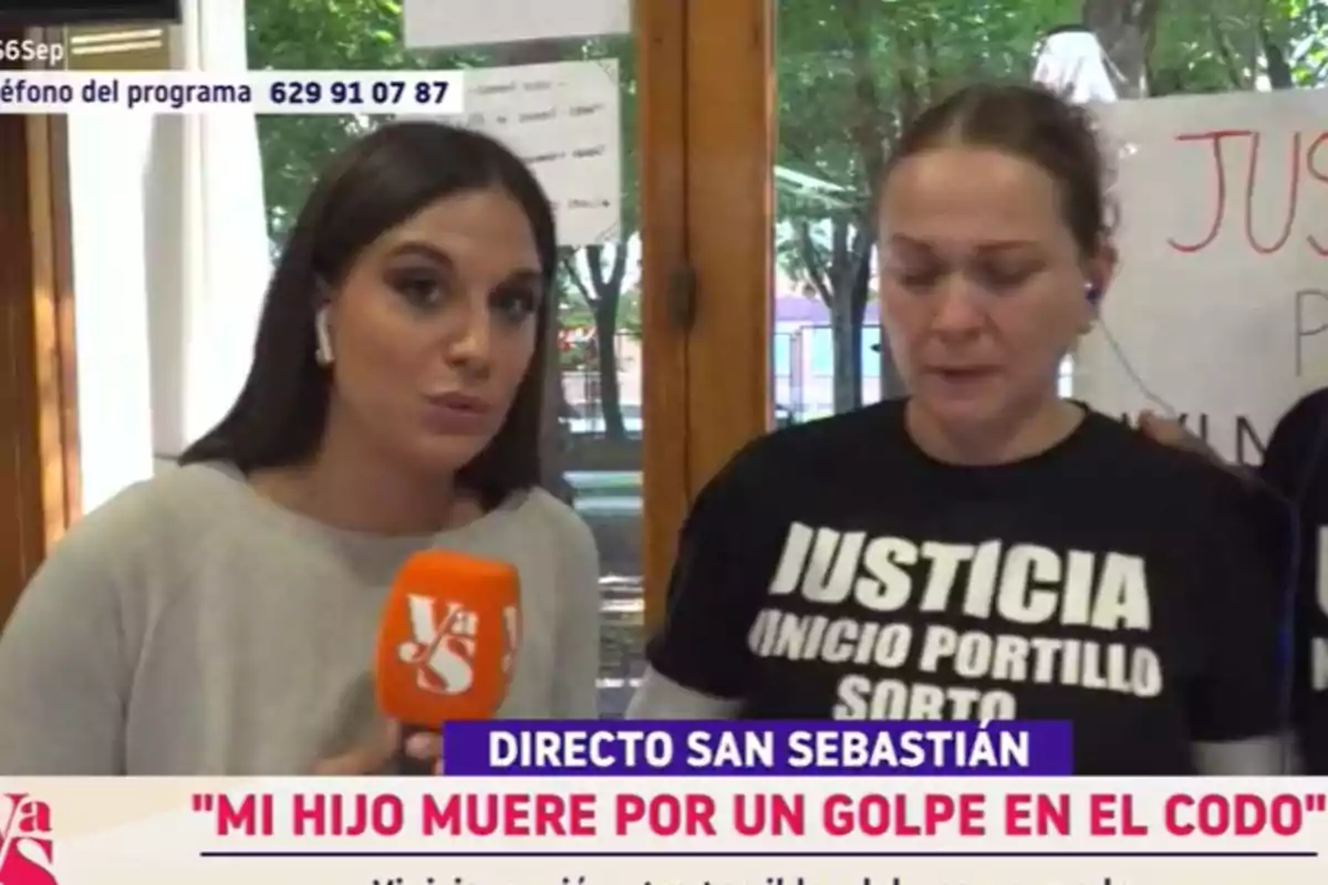 Una reportera entrevista a una mujer que lleva una camiseta negra con la palabra justicia impresa, ambas están en un lugar cerrado con ventanas y carteles al fondo, y en la parte inferior de la imagen aparece un titular sobre la muerte de un hijo. Una reportera entrevista a una mujer que lleva una camiseta negra con la palabra justicia impresa, ambas están en un lugar cerrado con ventanas y carteles al fondo, y en la parte inferior de la imagen aparece un titular sobre la muerte de un hijo.
