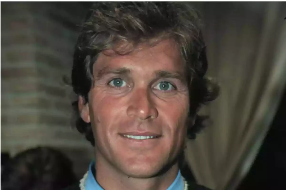 Brown-haired man with blue eyes smiling at the camera in an indoor setting