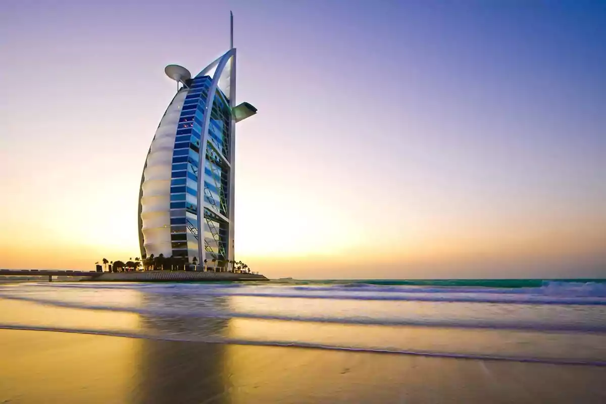 Edificio moderno junto al mar al atardecer con cielo despejado y reflejo en la arena mojada Edificio moderno junto al mar al atardecer con cielo despejado y reflejo en la arena mojada