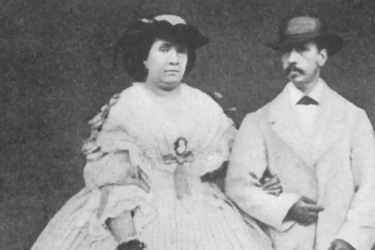 Pareja vestida con ropa de época posando para una fotografía antigua en blanco y negro Pareja vestida con ropa de época posando para una fotografía antigua en blanco y negro