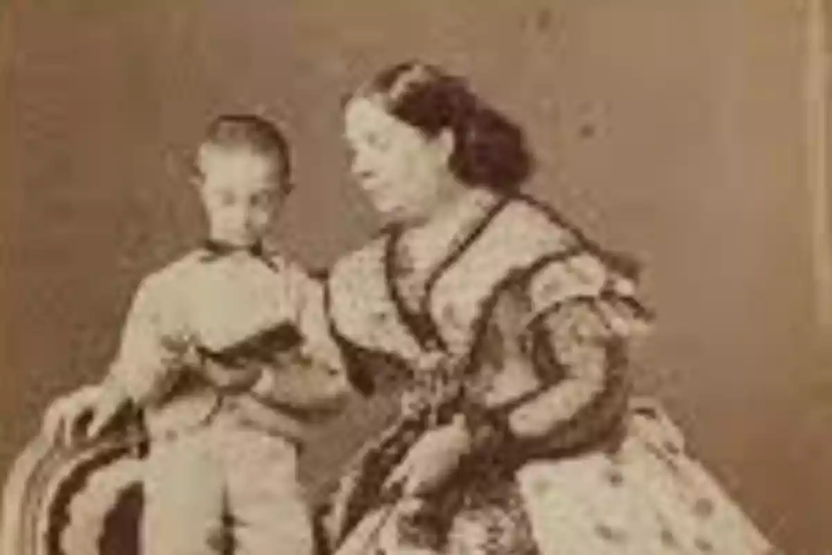 Fotografía antigua en sepia de una mujer sentada junto a un niño que sostiene un libro Fotografía antigua en sepia de una mujer sentada junto a un niño que sostiene un libro