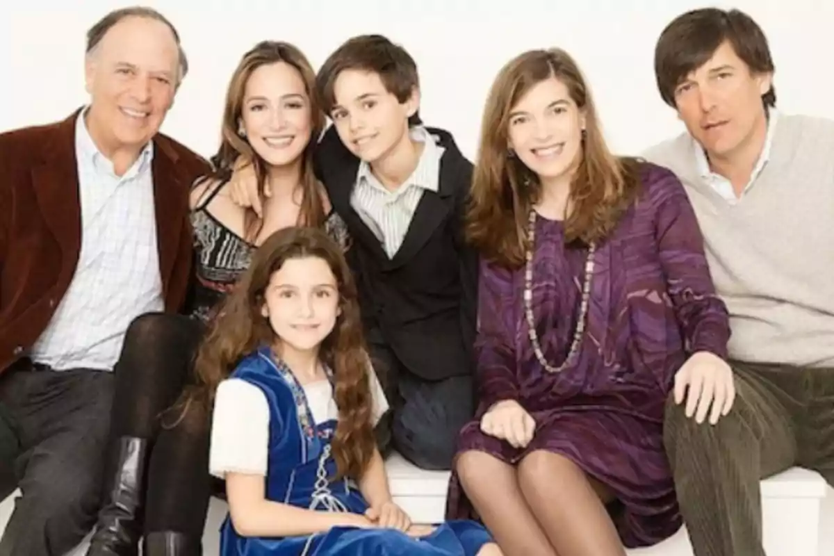 Grupo de seis personas de diferentes edades posando juntas y sonriendo frente a un fondo blanco Grupo de seis personas de diferentes edades posando juntas y sonriendo frente a un fondo blanco