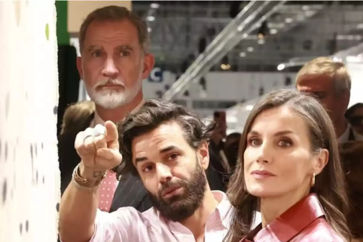 Tres personas observan atentamente una obra de arte en una galería mientras una de ellas señala hacia el cuadro Tres personas observan atentamente una obra de arte en una galería mientras una de ellas señala hacia el cuadro