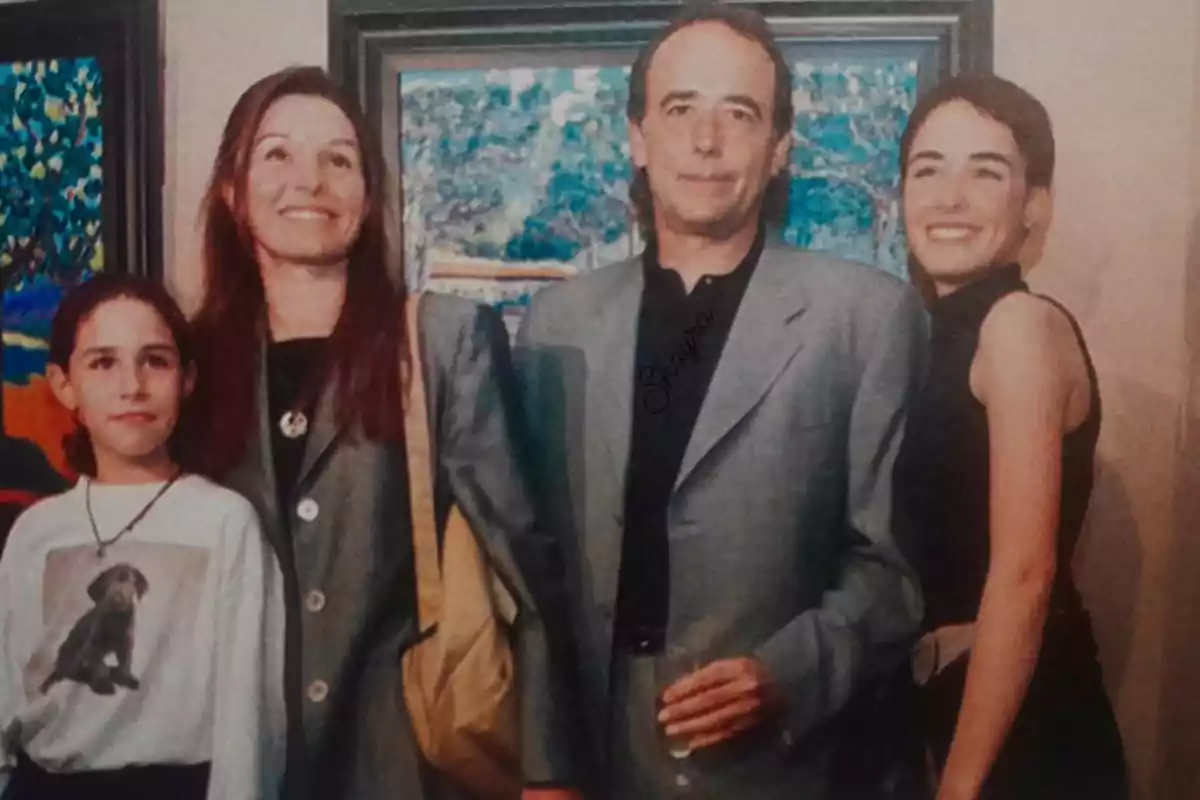 Cuatro personas posan sonrientes frente a cuadros coloridos en una galería de arte, una niña lleva una camiseta con la imagen de un perro y un hombre sostiene un vaso en la mano. Cuatro personas posan sonrientes frente a cuadros coloridos en una galería de arte, una niña lleva una camiseta con la imagen de un perro y un hombre sostiene un vaso en la mano.