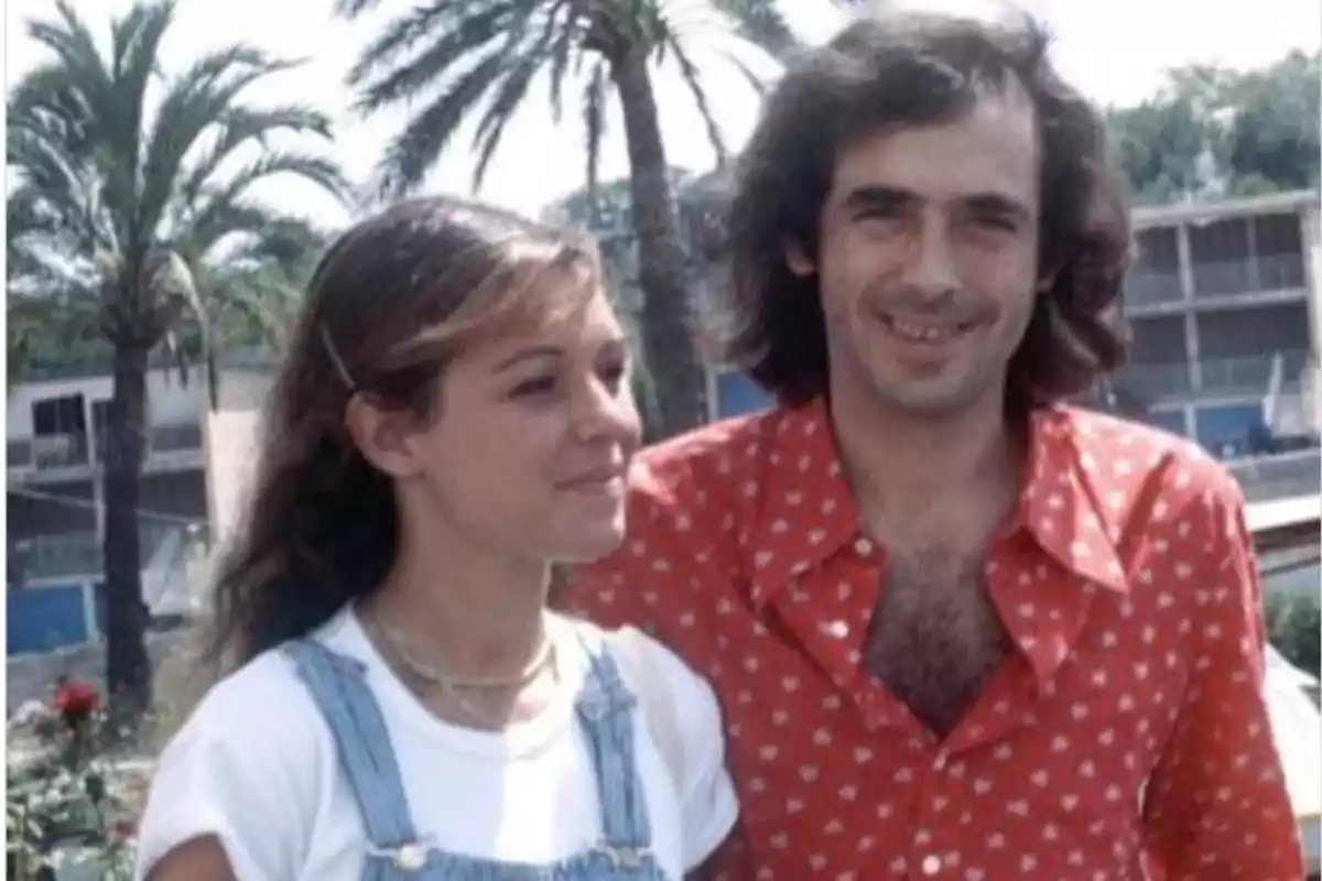 Una joven y un hombre posan juntos al aire libre con palmeras y edificios al fondo en un día soleado Una joven y un hombre posan juntos al aire libre con palmeras y edificios al fondo en un día soleado
