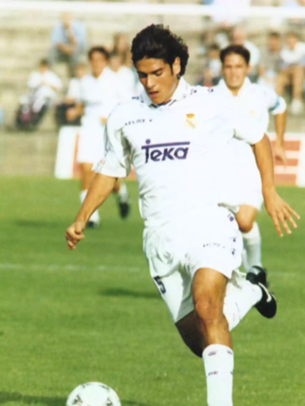 Futbolista con uniforme blanco del Real Madrid corriendo en el campo y controlando el balón durante un partido Futbolista con uniforme blanco del Real Madrid corriendo en el campo y controlando el balón durante un partido