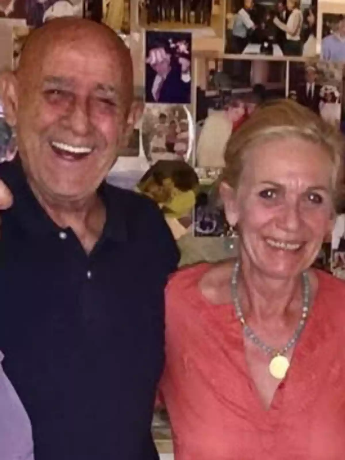 Pareja de personas mayores sonriendo frente a una pared llena de fotografías familiares Pareja de personas mayores sonriendo frente a una pared llena de fotografías familiares