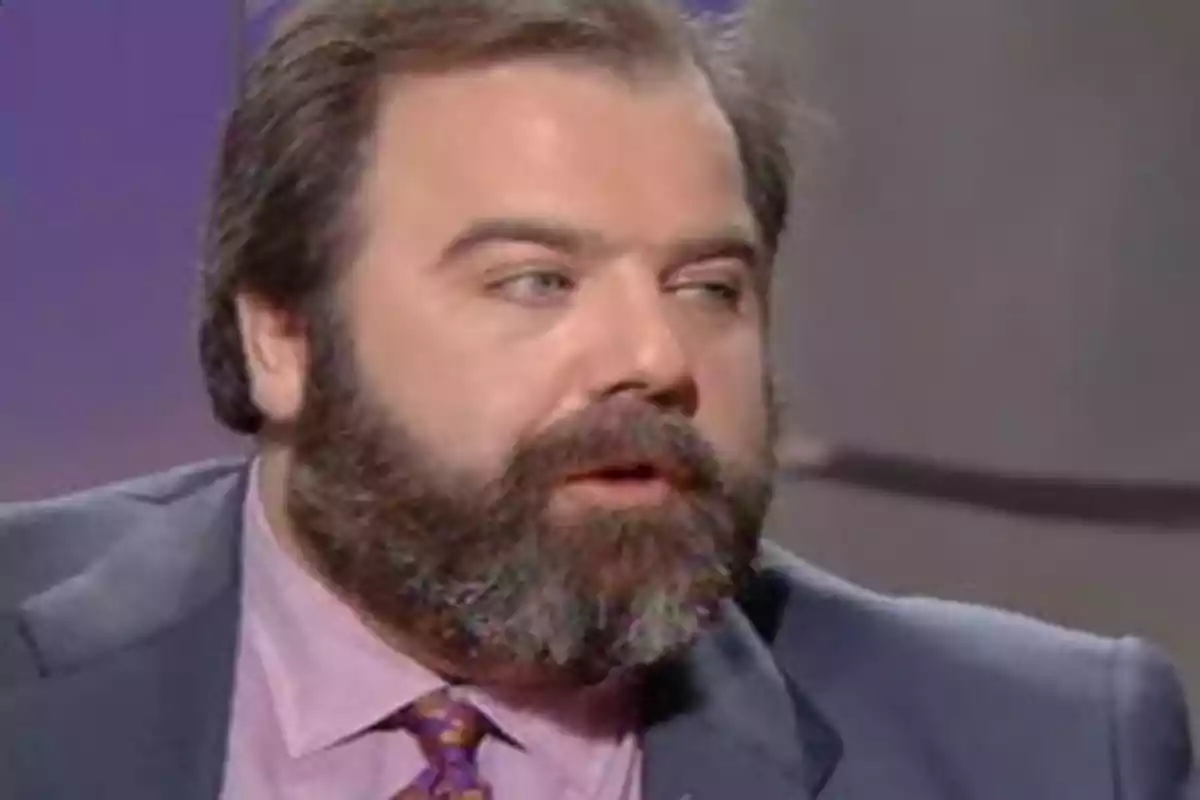 Hombre de barba y cabello oscuro con traje y corbata en un entorno de estudio televisivo Hombre de barba y cabello oscuro con traje y corbata en un entorno de estudio televisivo