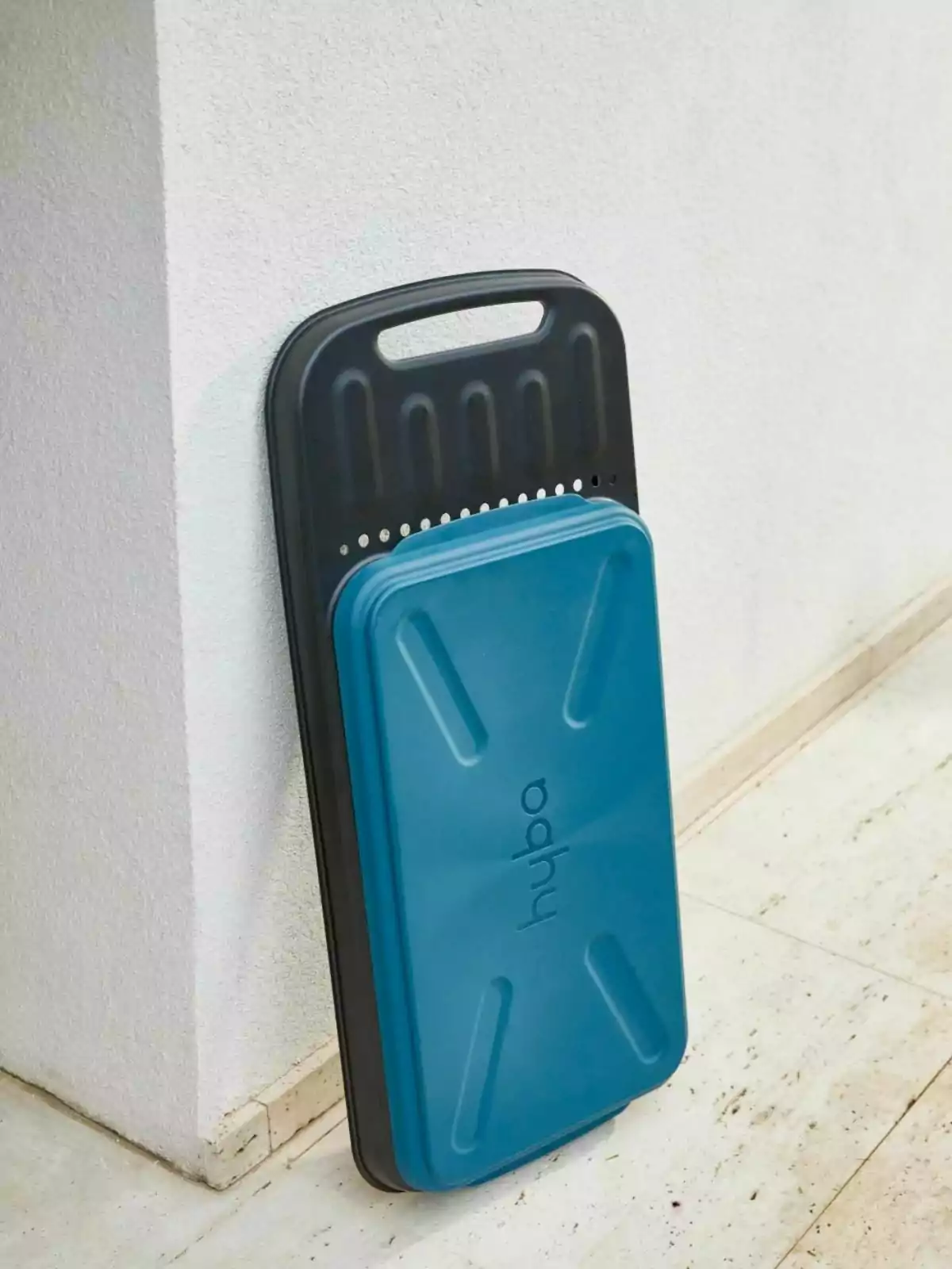 Banco de ejercicio azul y negro apoyado contra una pared blanca sobre un piso de mármol Banco de ejercicio azul y negro apoyado contra una pared blanca sobre un piso de mármol