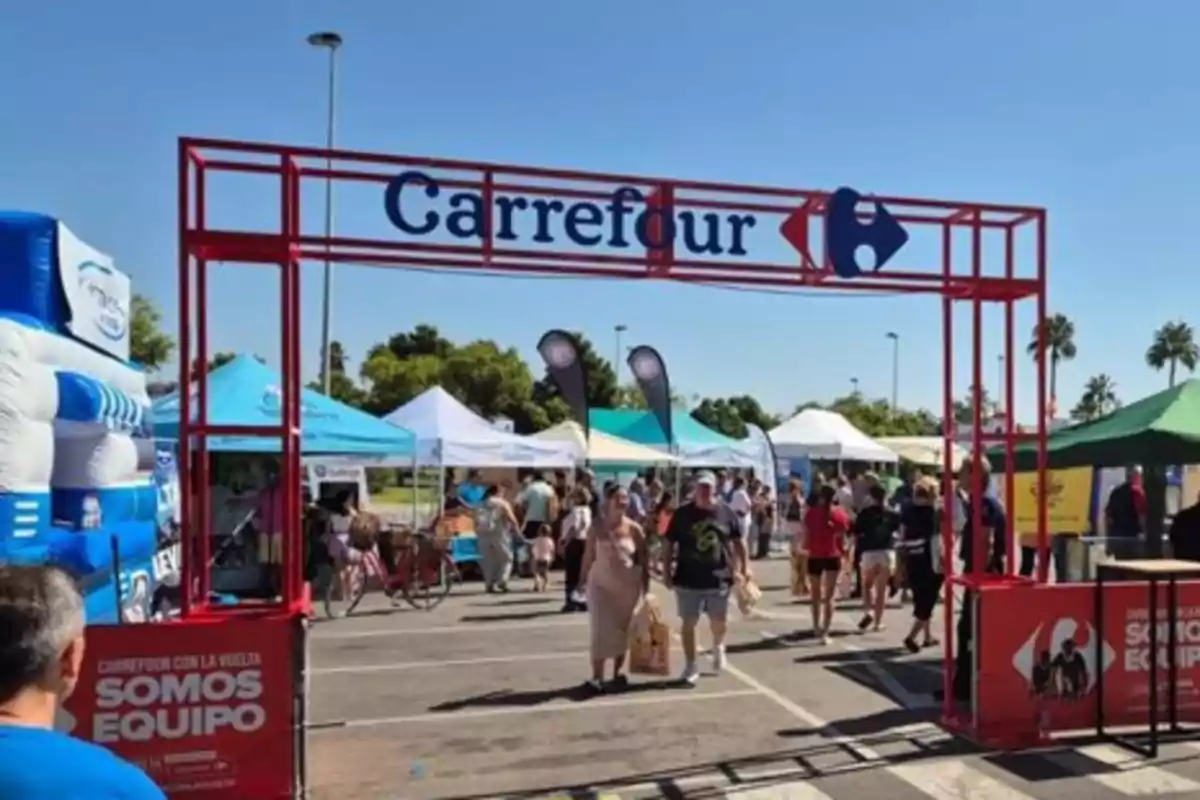 Entrada a un evento al aire libre organizado por Carrefour con varias personas caminando y diferentes carpas de colores en el fondo Entrada a un evento al aire libre organizado por Carrefour con varias personas caminando y diferentes carpas de colores en el fondo