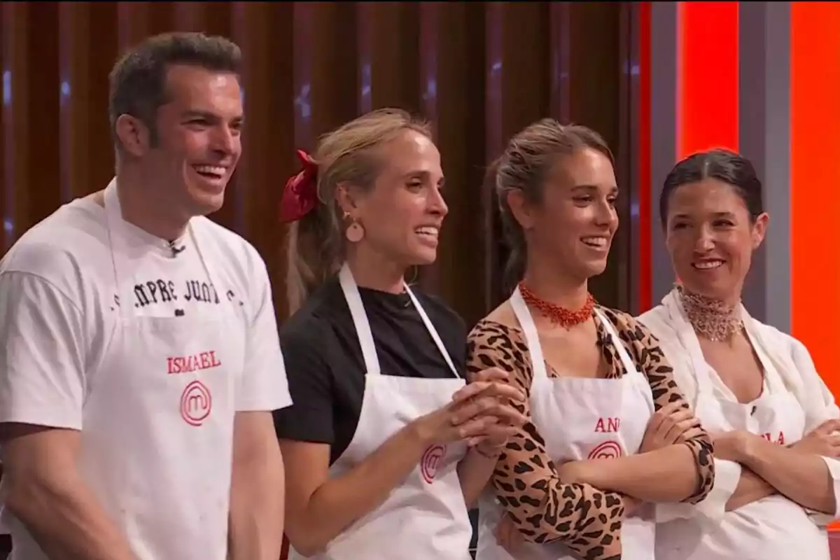Cuatro personas -que son concursantes de 'MasterChef' 2025- sonríen y llevan delantales blancos de cocina en un set de concurso.