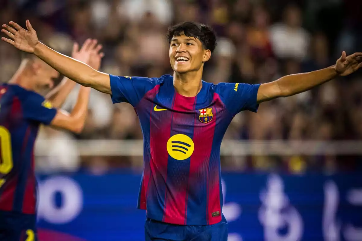 Jugador del Barcelona celebrando un gol con los brazos abiertos y una gran sonrisa en el rostro durante un partido