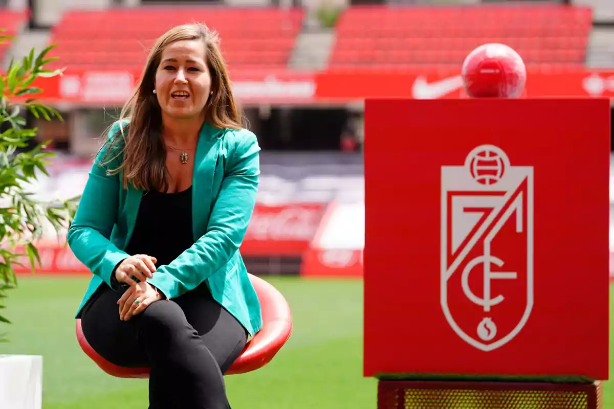 Mujer sentada en una silla en un estadio de fútbol junto a un cubo rojo con el escudo del Granada CF Mujer sentada en una silla en un estadio de fútbol junto a un cubo rojo con el escudo del Granada CF