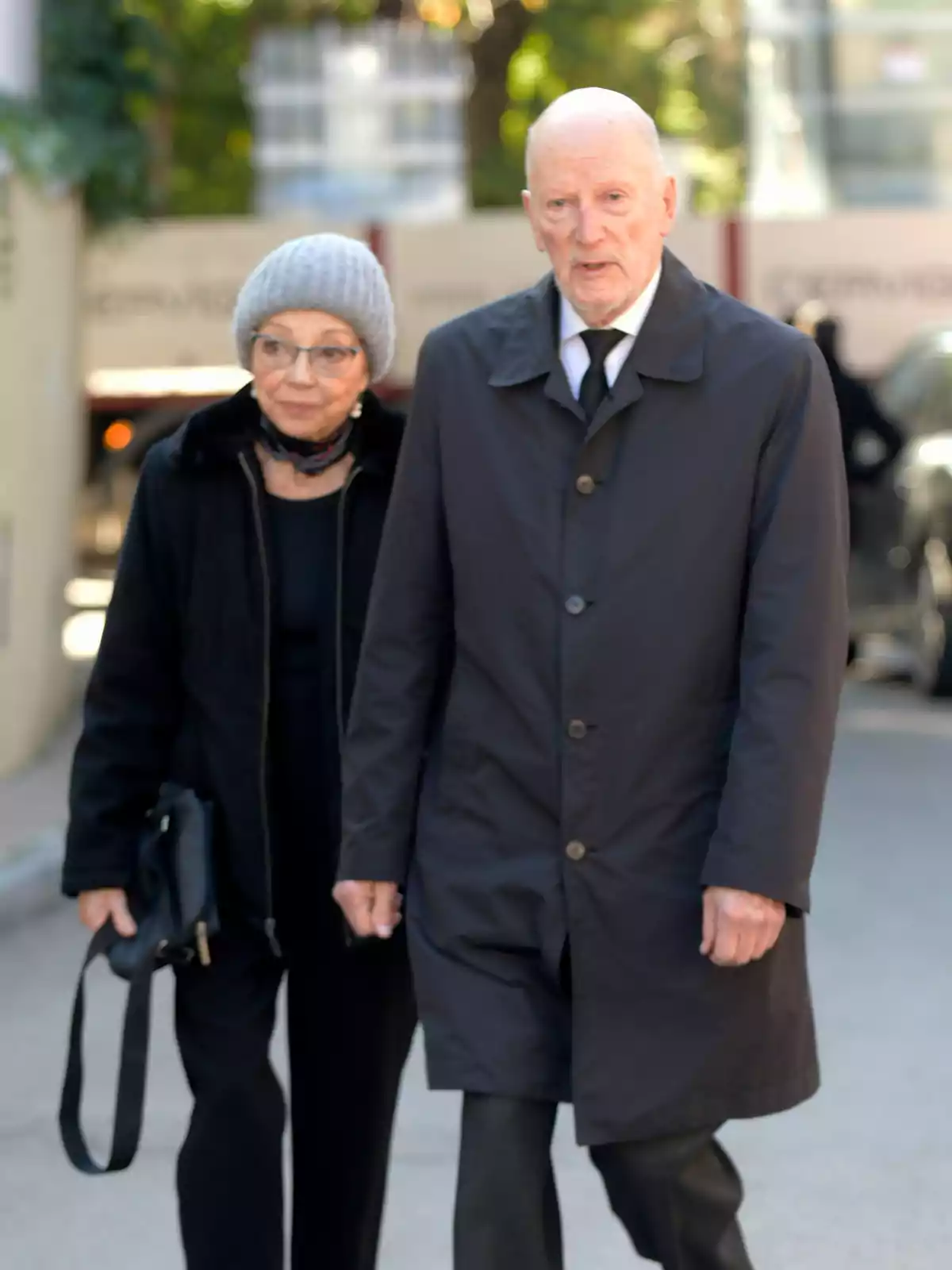 Una pareja de personas mayores camina por la calle vestida con ropa oscura y abrigada Una pareja de personas mayores camina por la calle vestida con ropa oscura y abrigada