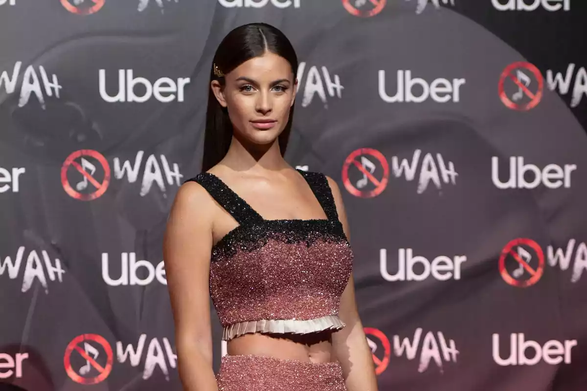Mujer con vestido brillante en un evento con fondo de logotipos de Uber y WAH Mujer con vestido brillante en un evento con fondo de logotipos de Uber y WAH