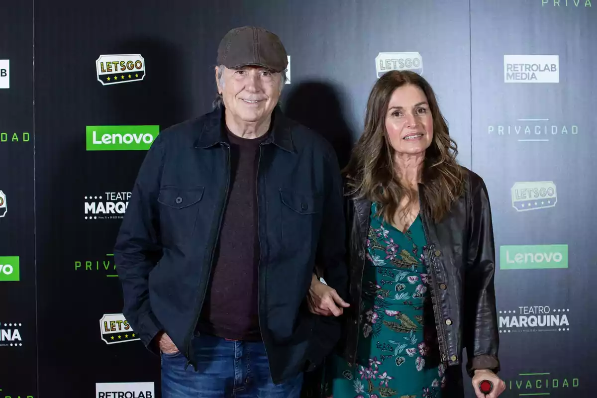 Una pareja posa sonriente en una alfombra roja frente a un fondo con logotipos de marcas y el nombre de un teatro Una pareja posa sonriente en una alfombra roja frente a un fondo con logotipos de marcas y el nombre de un teatro