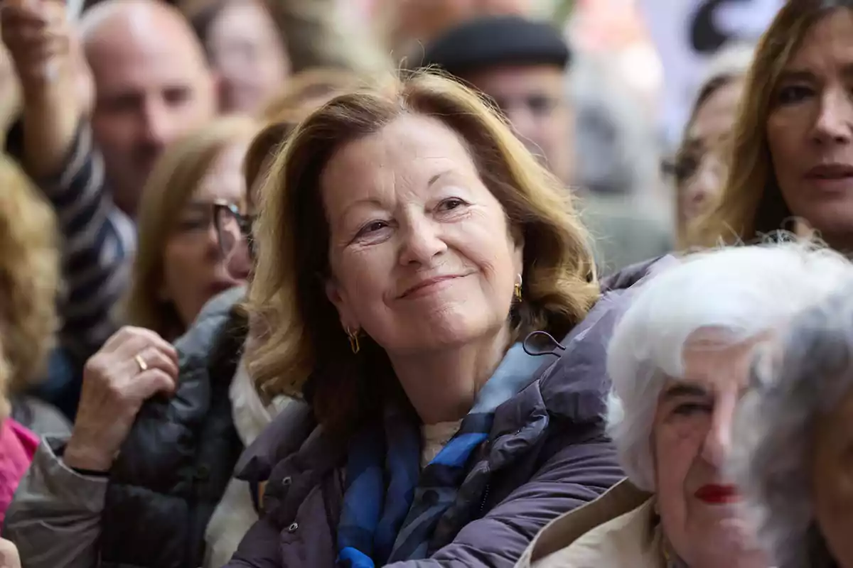Mujer mayor sonriente en medio de una multitud durante un evento al aire libre Mujer mayor sonriente en medio de una multitud durante un evento al aire libre