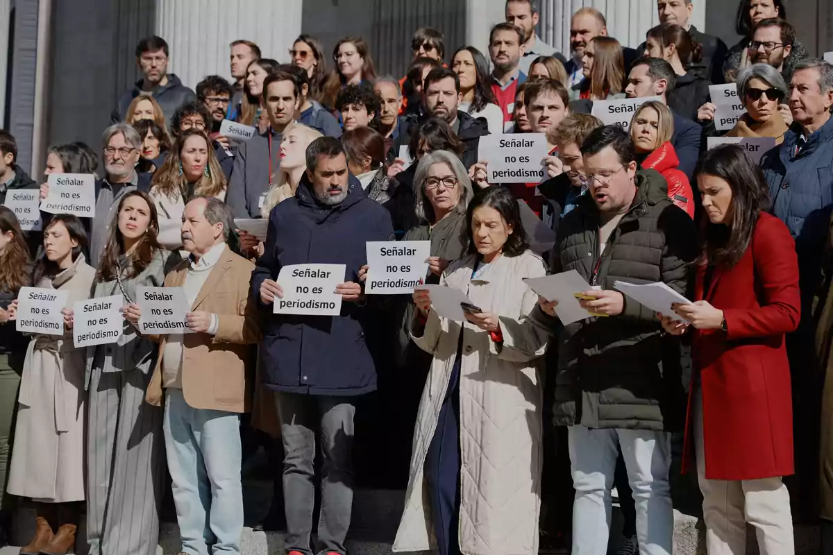 Un grupo numeroso de personas se manifiesta en unas escaleras sosteniendo carteles que dicen Señalar no es periodismo Un grupo numeroso de personas se manifiesta en unas escaleras sosteniendo carteles que dicen Señalar no es periodismo
