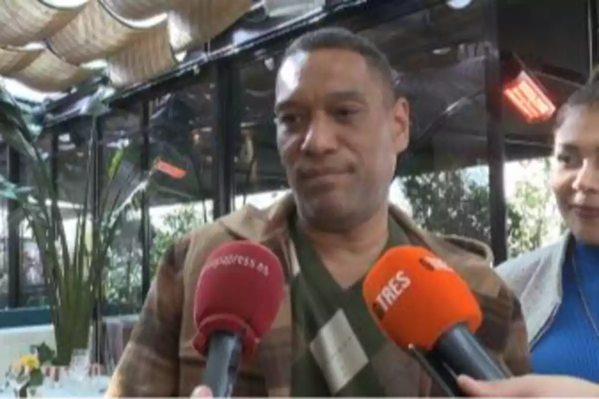 Hombre siendo entrevistado por varios medios de comunicación en un lugar cerrado con plantas al fondo Hombre siendo entrevistado por varios medios de comunicación en un lugar cerrado con plantas al fondo
