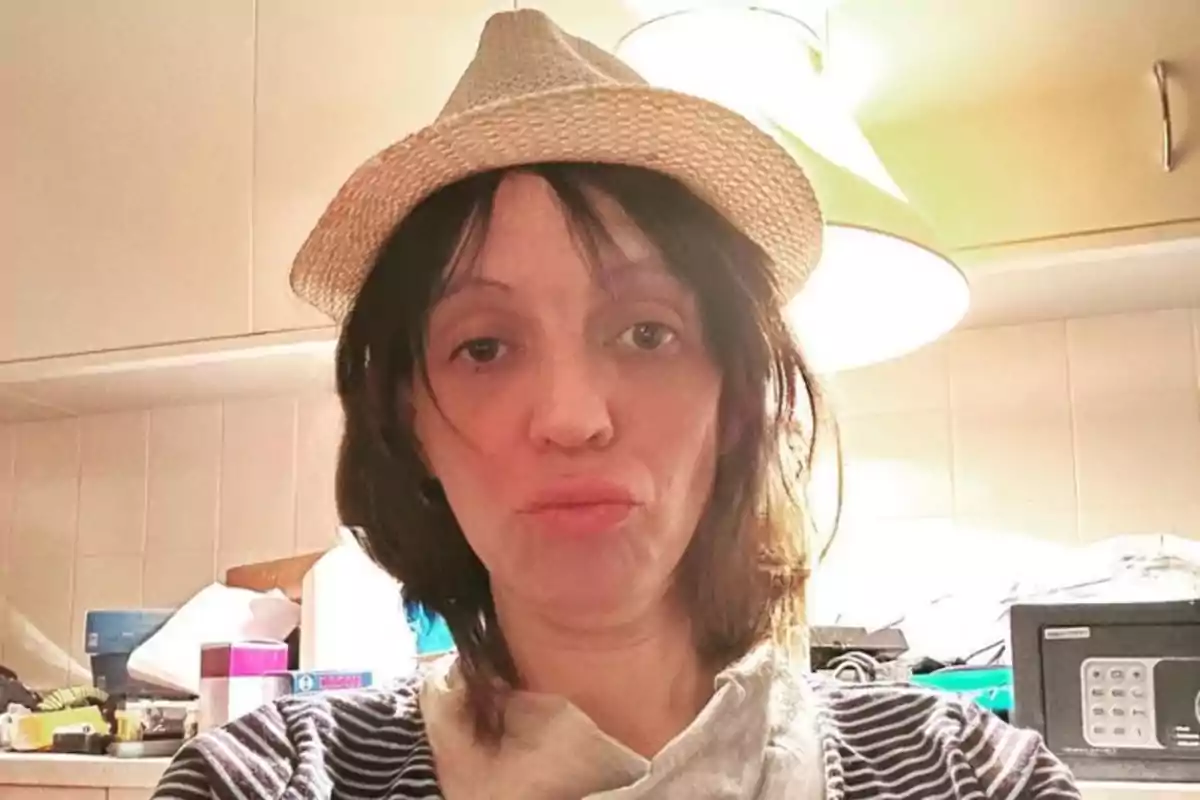 Mujer con sombrero de paja y camiseta de rayas posando en una cocina iluminada