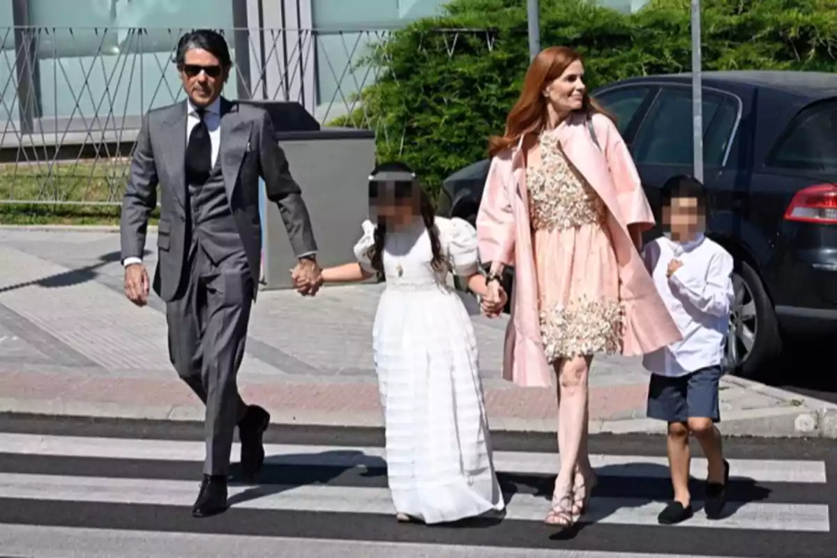 Familia elegantemente vestida cruzando una calle juntos en un paso de peatones en un día soleado Familia elegantemente vestida cruzando una calle juntos en un paso de peatones en un día soleado