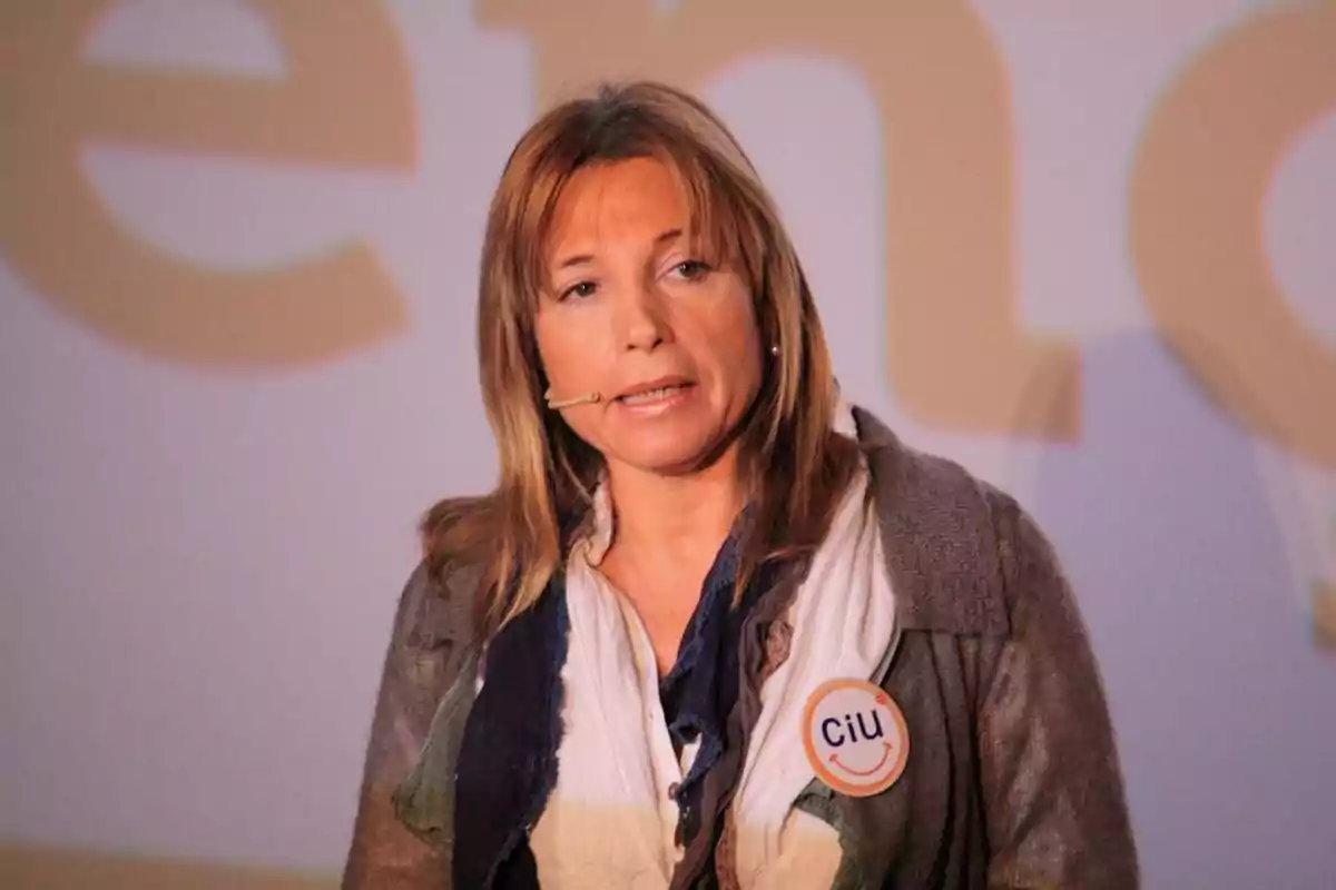 Mujer con micrófono de diadema y chapa de ciu en la ropa hablando en un evento Mujer con micrófono de diadema y chapa de ciu en la ropa hablando en un evento