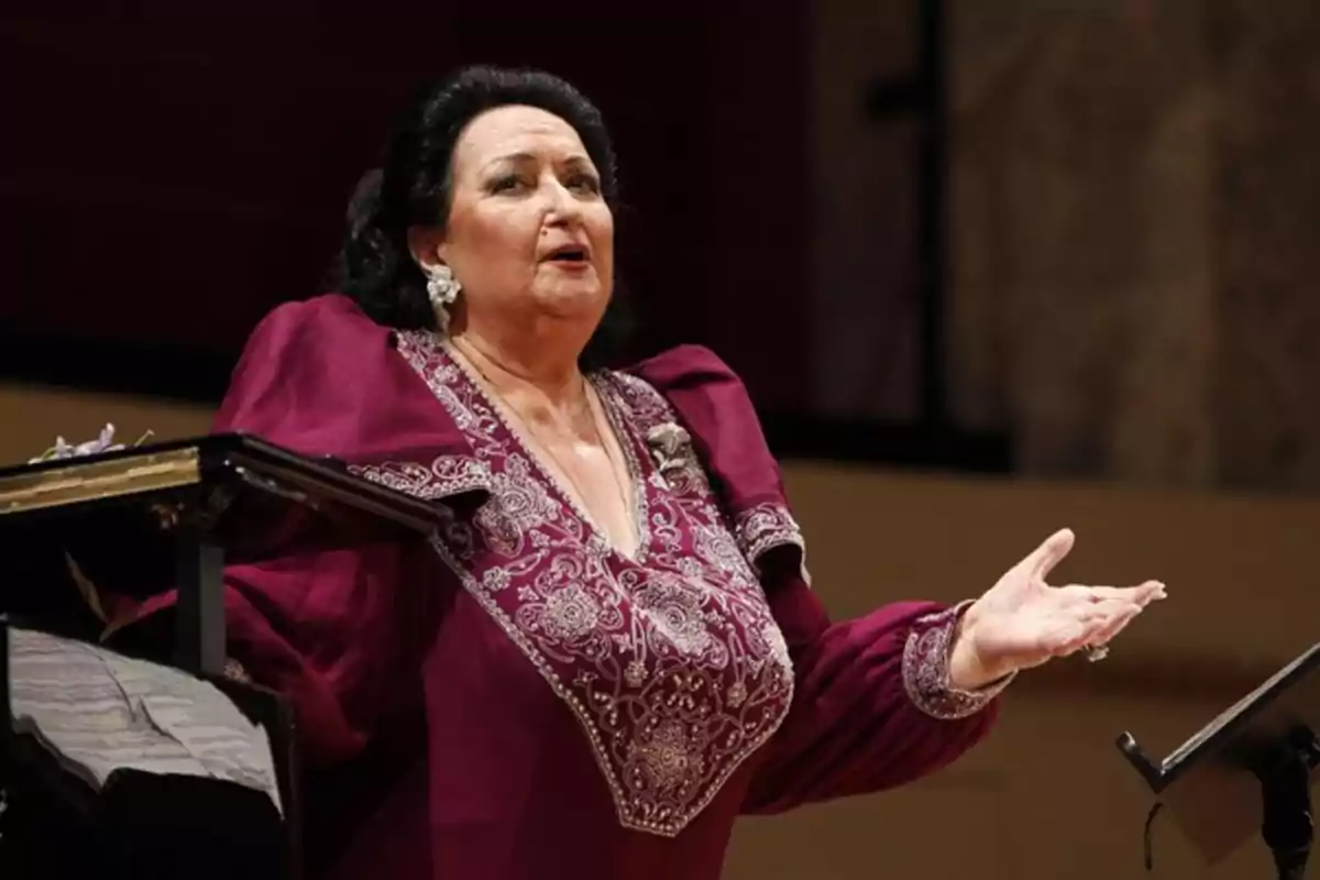Mujer de cabello oscuro vestida con un elegante vestido morado bordado cantando en un escenario