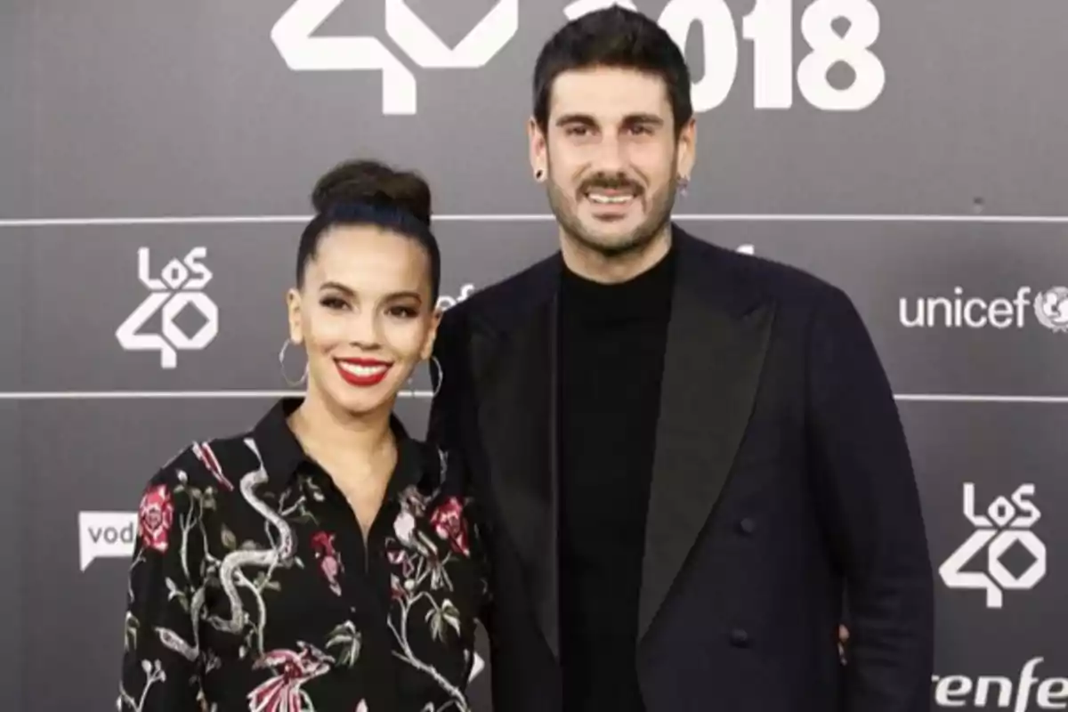 Una pareja posando en la alfombra roja de un evento de Los 40 en 2018