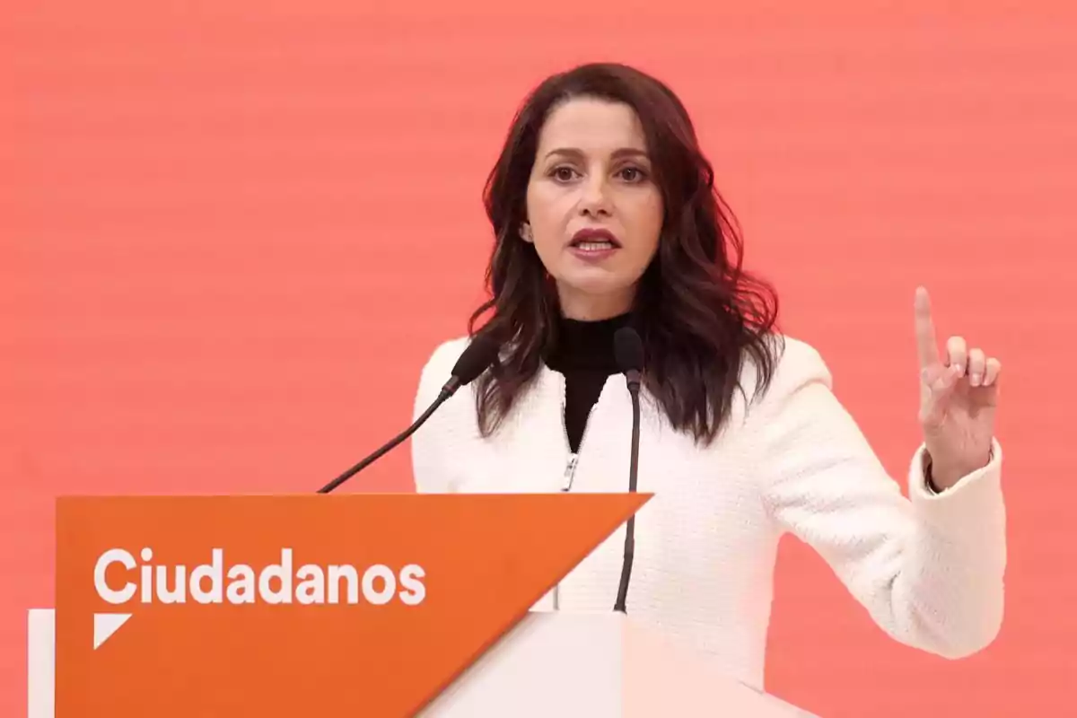 Woman speaking at a podium with the Ciudadanos logo against an orange background